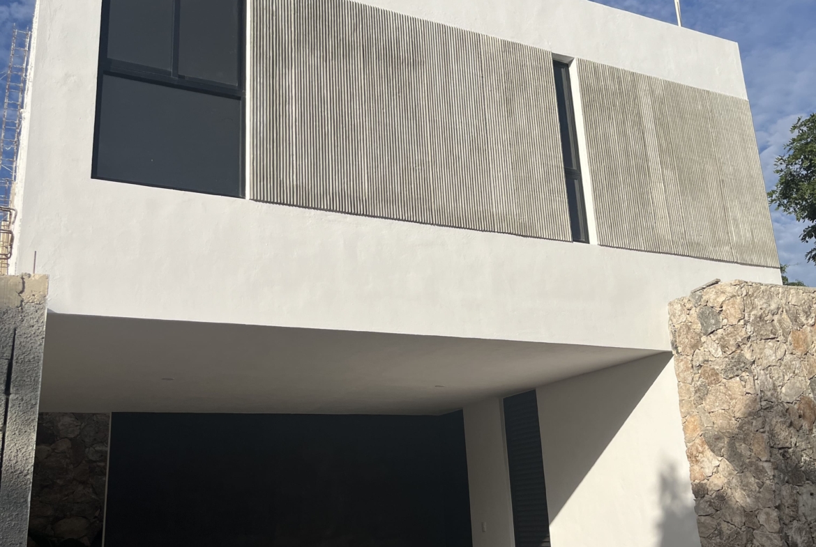 a white building with a stone wall and a black door