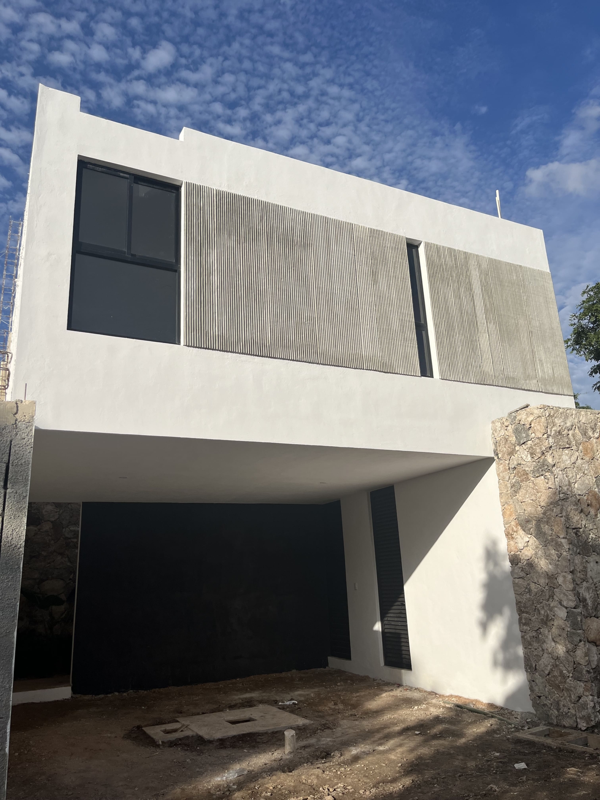 a white building with a stone wall and a black door